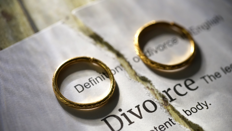 Dwie złote obrączki na rozerwanej kartce z napisem Divorce